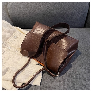 Détail d'un sac cabas marron foncé à motif crocodile avec large bandoulière sur canapé