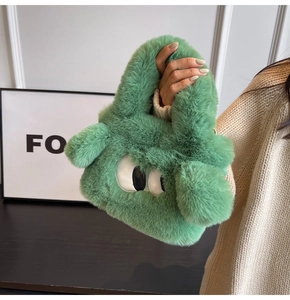 Close-up of fluffy green monster handbag with cartoon eye details and soft faux fur texture
