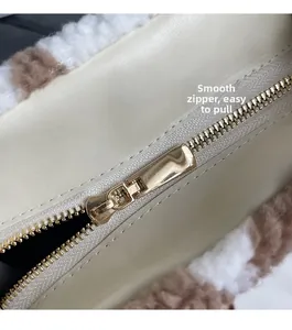 Detail of smooth gold zipper on beige leather tote bag with soft faux fur trim