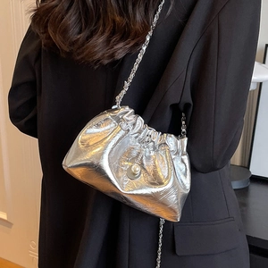 Silver metallic drawstring cloud bag with pearl charm shown on a model in a black blazer
