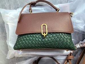 Detail of the green woven leather texture and golden metal ring buckle on the crossbody bag