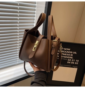 Détail du sac seau en cuir marron grainé avec fermoir doré et bandoulière réglable