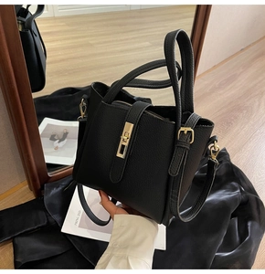 Détail du sac seau en cuir grainé noir avec un fermoir rotatif en métal doré élégant