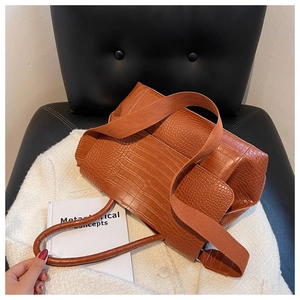Détail du cabas marron à motif crocodile avec double bandoulière sur tissu de laine blanc