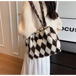 Detail of plush checkerboard tote bag with woven leather strap and branded label