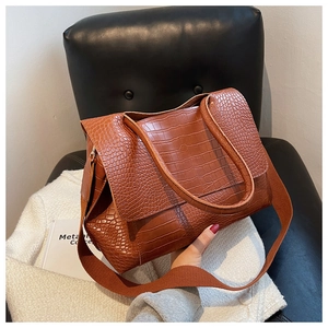 Gros plan d'un sac cabas marron effet crocodile avec large bandoulière sur cuir