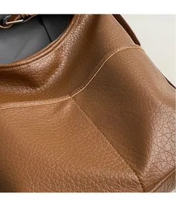 Gros plan sur la texture du cuir grainé marron et coutures soignées du sac seau