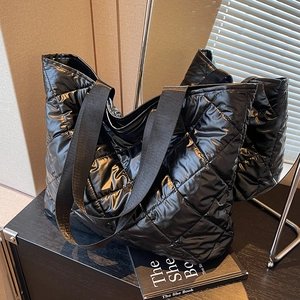 Black quilted tote bag with glossy finish and mirror reflection display in studio