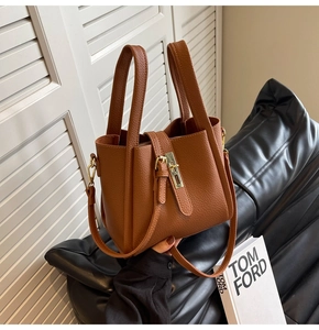 Détail d'un sac seau en cuir marron à motif litchi avec une boucle dorée élégante