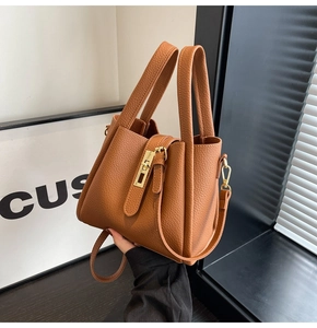 Détail d'un sac seau en cuir grainé marron avec boucle dorée et poignée courte