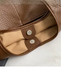 Détail du fermoir magnétique et des coutures sur un sac seau marron en cuir grainé