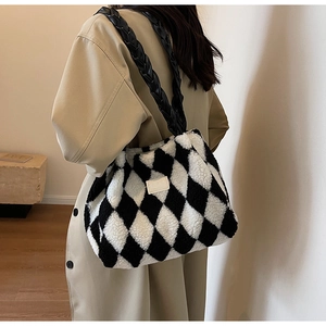 Detail of a plush tote bag featuring black and white checkered pattern and woven strap