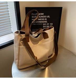 Detailed close-up of canvas tote bag showing brown straps and side metal D-ring buckle