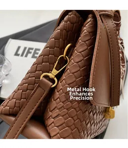 Close-up of brown woven square handbag with gold hardware and decorative silk scarf