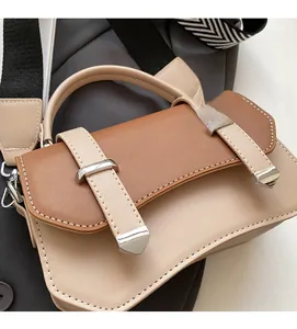 Close-up of contrast crossbody bag featuring metallic buckles and wide woven strap