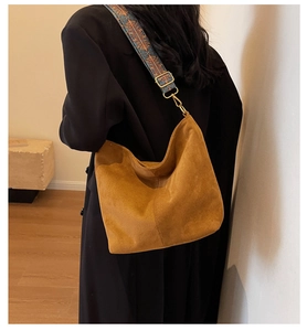 Detail of bohemian embroidered wide strap on tan faux suede tote bag with gold buckle