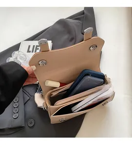 Detail view of small square crossbody bag with multiple interior storage compartments