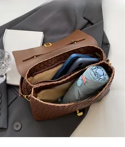 Detail view of brown woven handbag interior with two main compartments and zipper divider