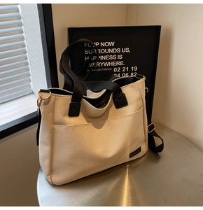 Detail of canvas tote bag showing large front pocket and contrasting black handles