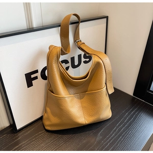 Détail de la texture cuir grainé marron et des poches latérales d'un sac seau
