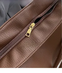 Close-up of golden zipper and lychee textured dark brown leather on tote bag