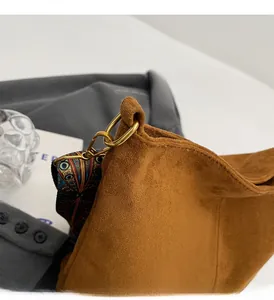 Detail of a brown suede tote bag featuring a gold round buckle and ethnic style strap