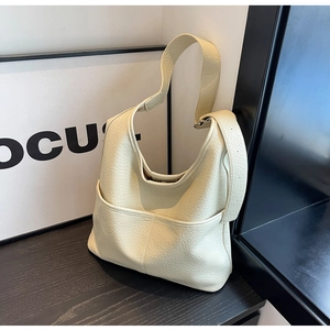 Détail du sac seau beige en cuir litchi avec bandoulière réglable sur support