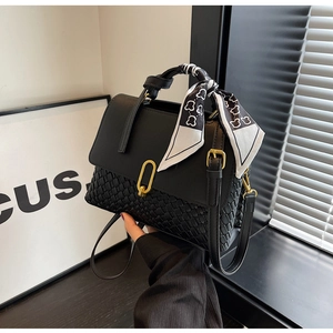 Detailed view of black woven handbag featuring a decorative bear print silk scarf