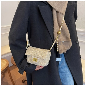 Detailed view of beige tweed crossbody bag with gold chain strap on a black blazer