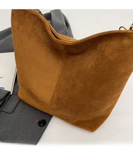 Detail of caramel brown matte tote bag with woven shoulder strap and soft suede texture
