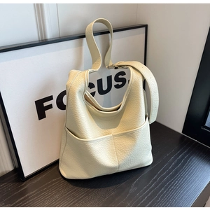 Détail du sac seau en cuir grainé crème avec poches avant symétriques et texture souple