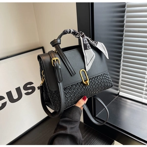 Detail of black woven leather handbag with gold U-buckle and silk scarf handle