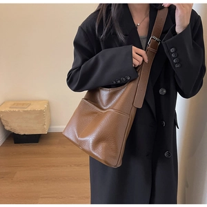 Détail du sac cabas en cuir marron avec texture litchi et bandoulière réglable