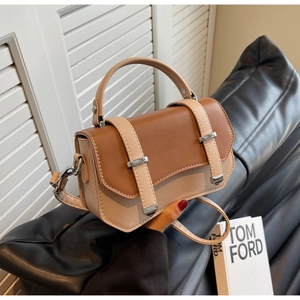 Detailed view of color-blocked leather crossbody bag with silver buckles and fine stitching