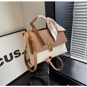 Detail of woven brown and white crossbody bag with metal lock and silk scarf on handle