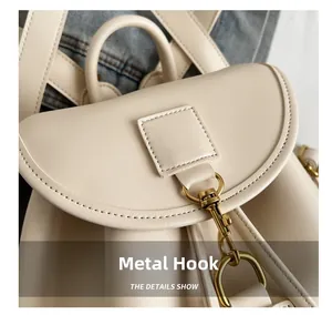 Gros plan sur le crochet en métal doré et la sangle en cuir blanc cassé du sac
