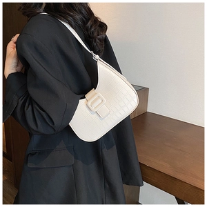 Detail of white crocodile pattern underarm bag showing texture and buckle on shoulder