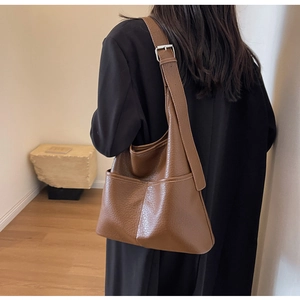 Détail d'un sac seau marron à motif litchi avec bandoulière et boucle en métal argenté