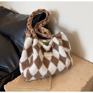 Detailed close-up of brown and white plush tote bag with a woven handle on a stone base