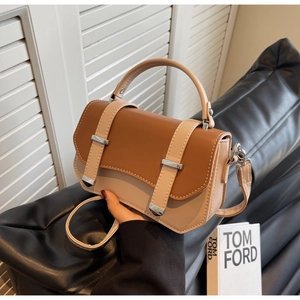 Close-up of contrast color handbag with metallic buckle and elegant top handle