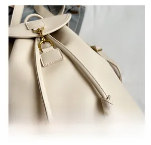 Détail du sac à dos en cuir beige montrant les boucles dorées et le cordon de serrage