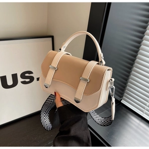 Detail view of the bi-color crossbody bag with wide striped strap and metal buckles