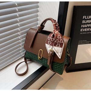 Detail of green woven crossbody bag with brown leather flap and silk scarf handle
