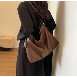 Side view of large brown pebble leather hobo bag worn by model for daily commute