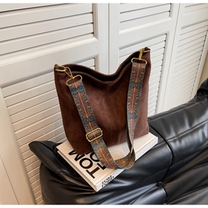 Close-up of brown suede tote bag featuring ethnic style woven wide shoulder strap