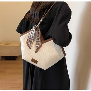 Macro shot of cream quilted tote bag featuring brown contrast trim and silk scarf