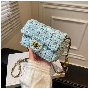 Detail of tweed crossbody bag with golden twist lock and chain strap on magazine