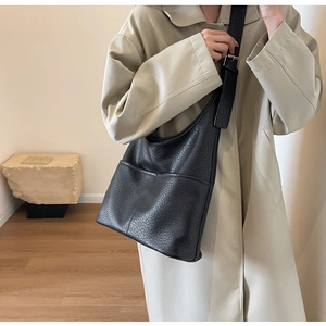 Détail du sac fourre-tout noir en cuir grainé avec bandoulière large et poche latérale