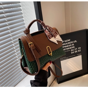 Detail of vintage woven leather handbag with contrast brown flap and gold metal clasp