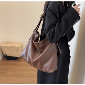 Close-up of caramel brown tote bag with litchi texture on a model in black suit